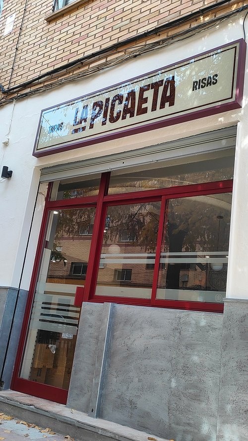 Fachada de La Picaeta, con su cartel «Tapas, La Picaeta, Risas» y la puerta granate